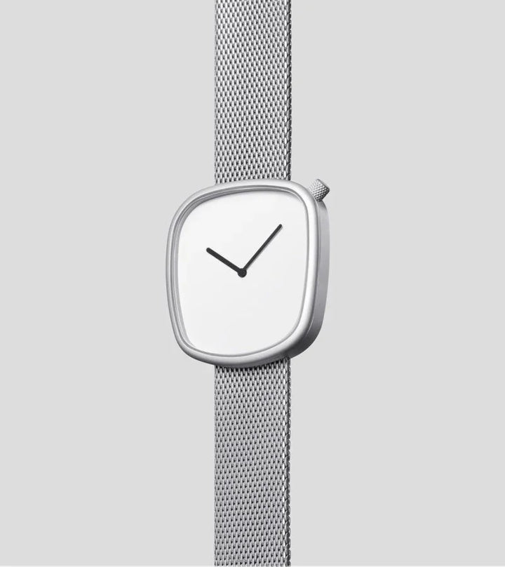 Minimalist silver wristwatch with an asymmetrical square face and mesh strap on gray background