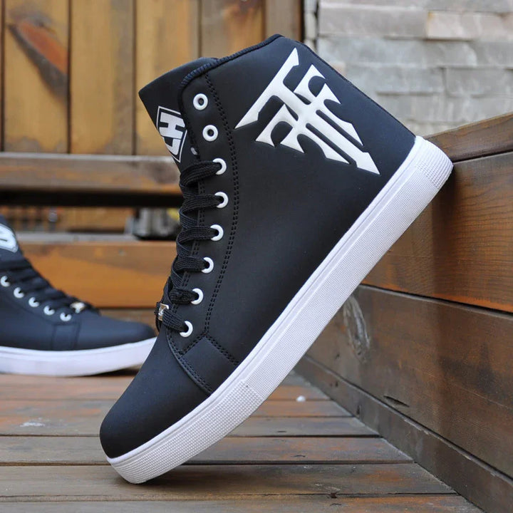 Black high-top sneakers with white sole and bold white graphic logo on side, displayed outdoors on wooden surface