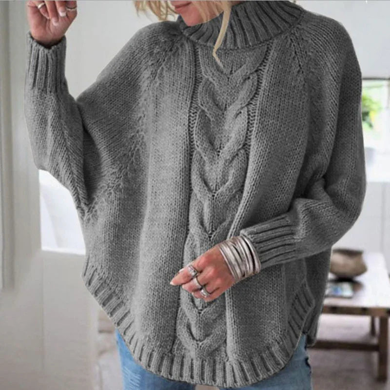 Woman wearing gray knit turtleneck sweater with cable pattern and ribbed cuffs indoors