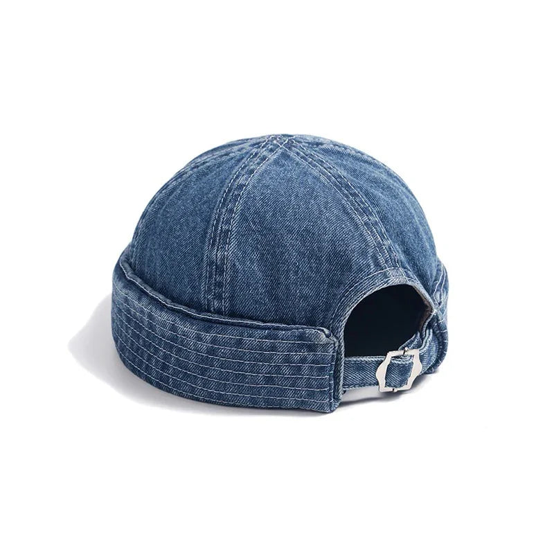 Blue denim docker cap with adjustable strap and silver buckle on white background