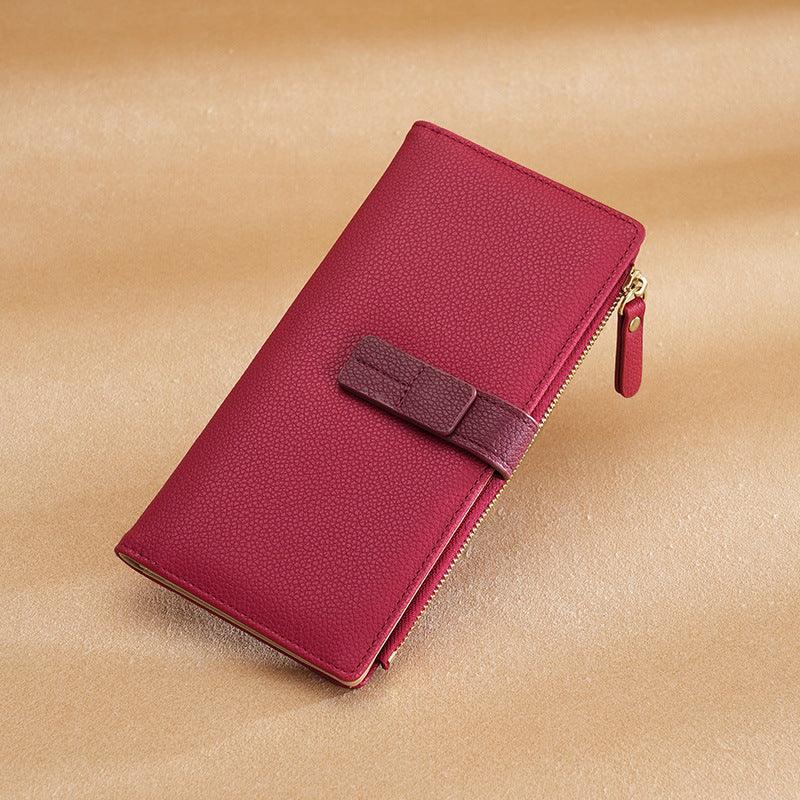 Elegant red leather wallet with textured surface, secure strap, and gold zipper on beige background