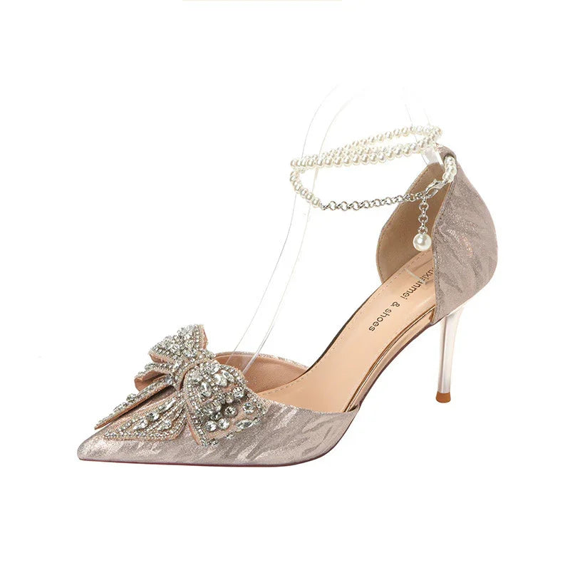 Elegant champagne satin high heel shoe with rhinestone bow and pearl ankle strap