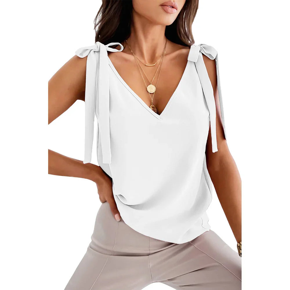Woman wearing white sleeveless V-neck top with shoulder ties and light beige pants