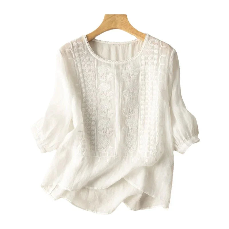 white semi-sheer embroidered blouse with puff sleeves on wooden hanger