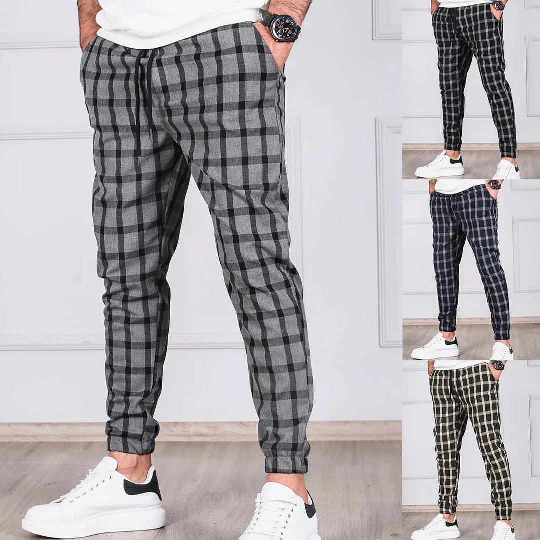 Men's slim-fit plaid jogger pants in gray, black, navy, and green displayed on model with white sneakers