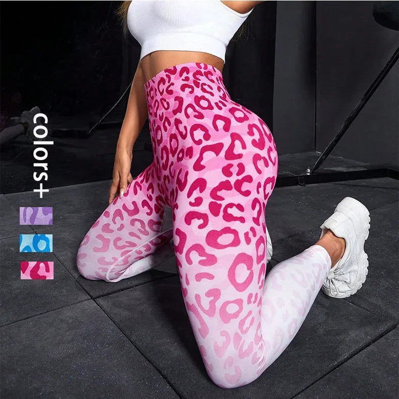Woman wearing pink leopard print high-waisted leggings and white crop top kneeling on gym floor