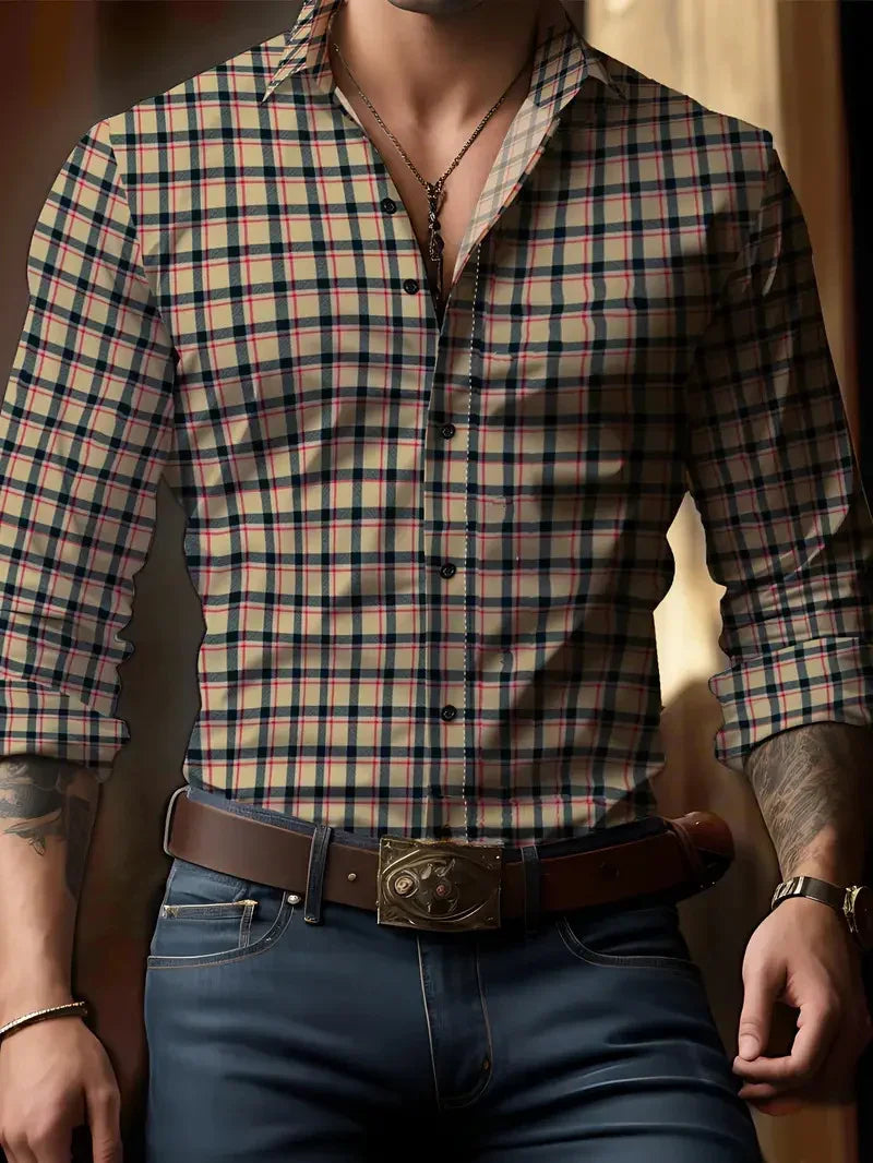 Man wearing beige plaid button-up shirt with rolled sleeves, blue jeans, brown leather belt, and chain necklace