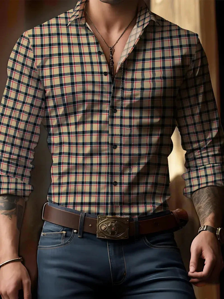 Man wearing beige plaid button-up shirt with rolled sleeves, blue jeans, brown leather belt, and chain necklace