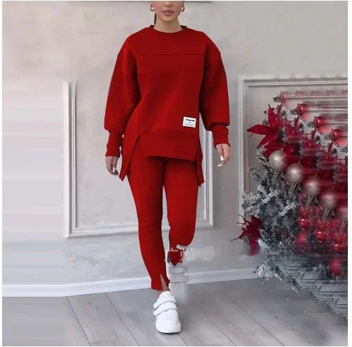 Woman wearing a red oversized sweater and matching pants walking indoors next to a decorated Christmas tree