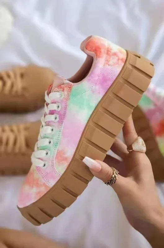 Hand holding a pastel tie-dye canvas sneaker with chunky tan platform sole and white laces