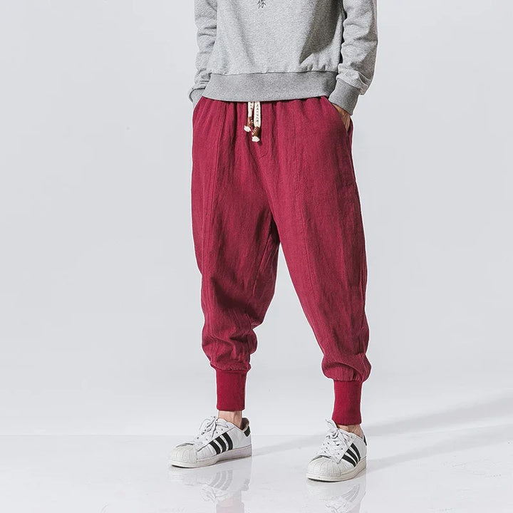Men's casual maroon cotton jogger pants with drawstring waist and elastic cuffs, paired with white sneakers