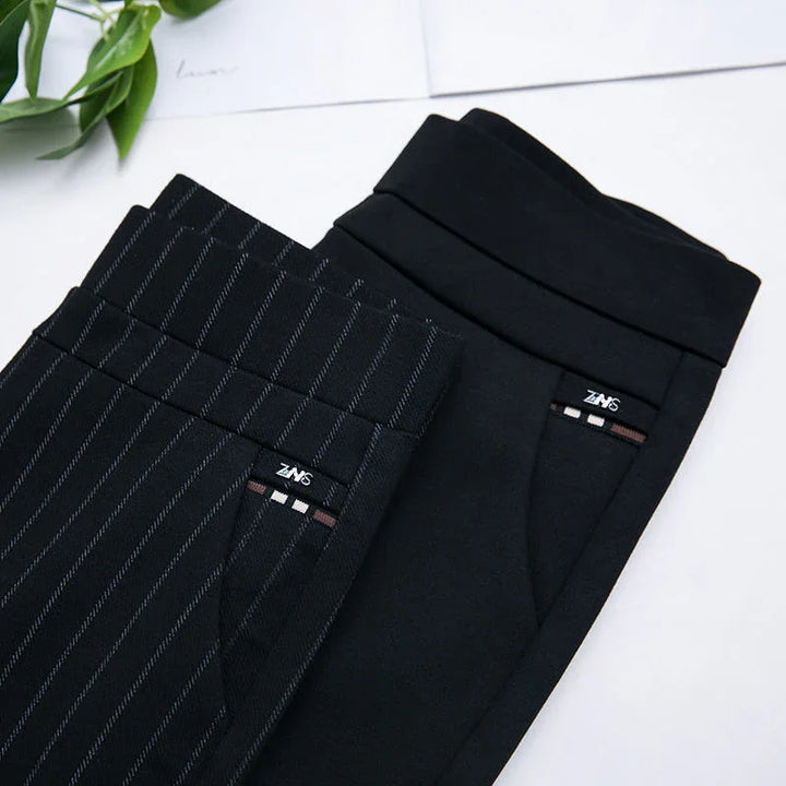 Two pairs of black pants, one solid and one pinstriped, folded with visible ZANS labels