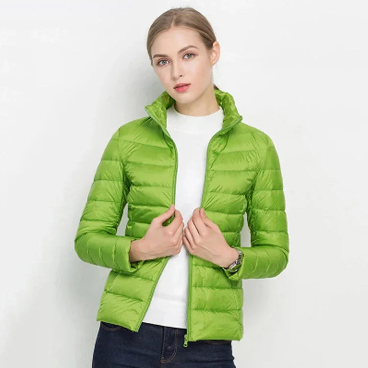 Woman wearing bright green lightweight puffer jacket over white top with dark jeans