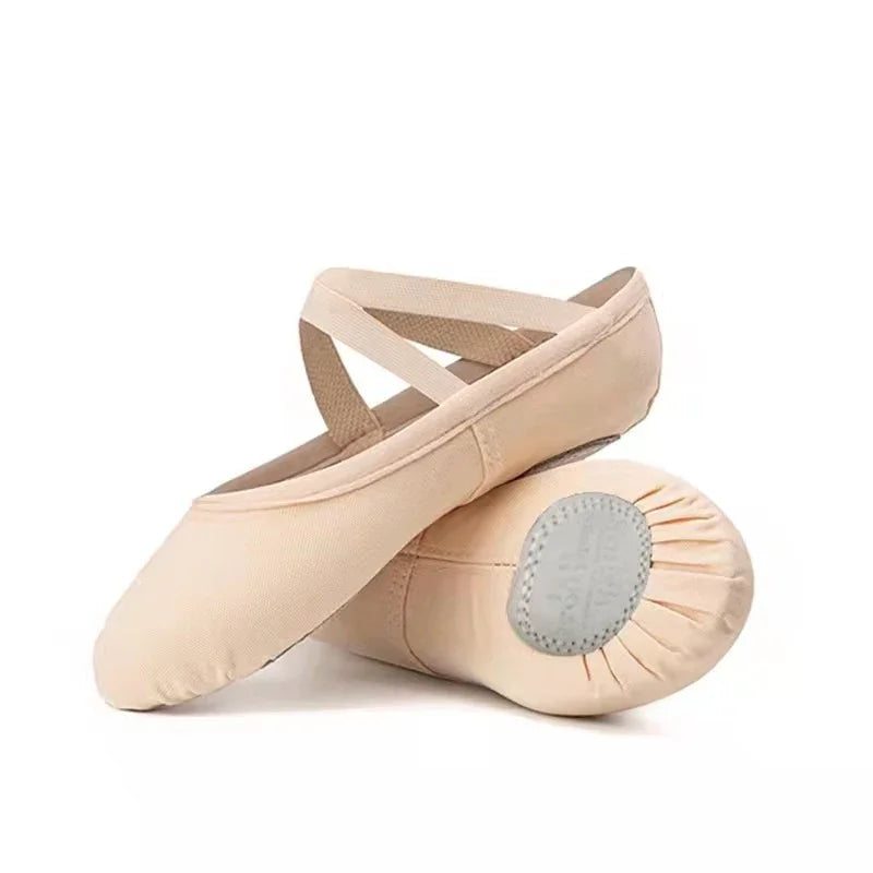Pair of beige ballet shoes with elastic crisscross straps and split sole on white background