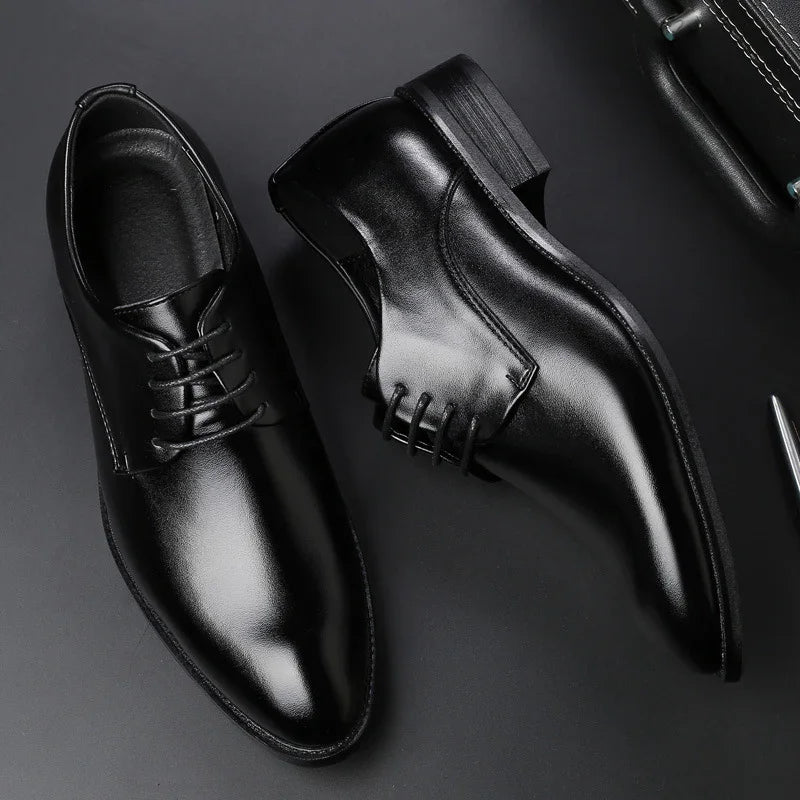 Pair of shiny black leather formal dress shoes with lace-up design on a black surface