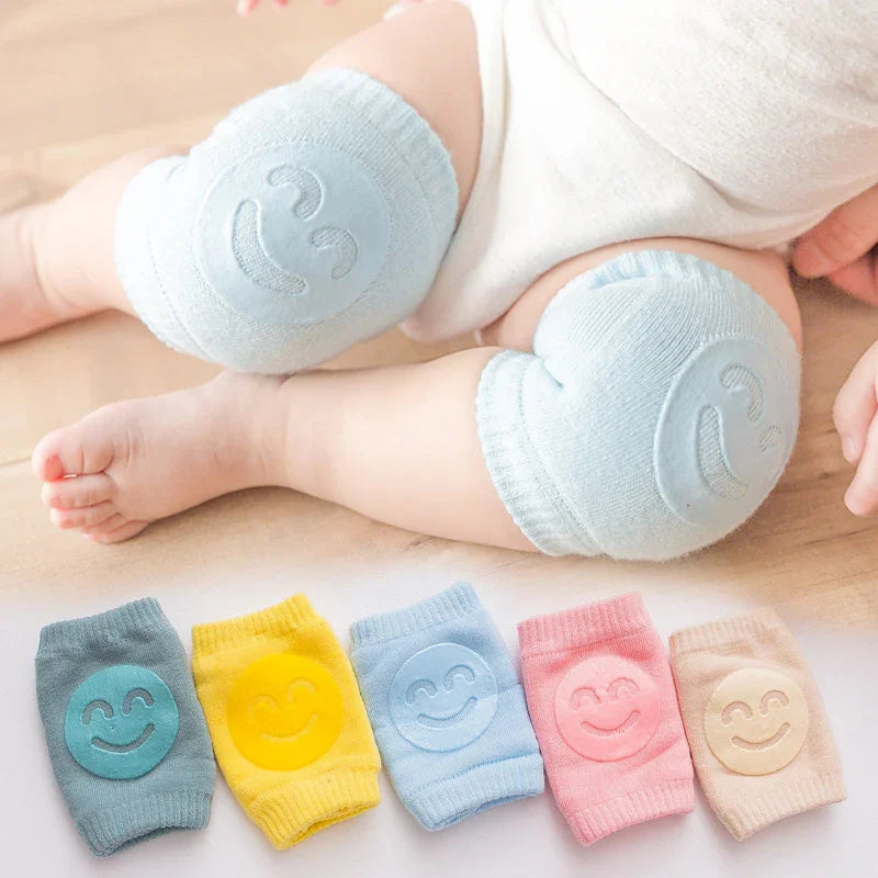 Baby wearing soft blue knee pads with smiley face design on wooden floor, colorful knee pad options below
