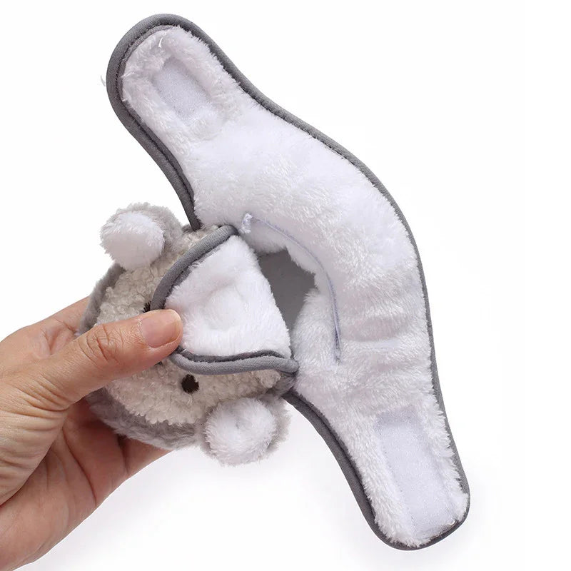 Hand holding a gray and white plush baby headband with velcro straps and bear ears