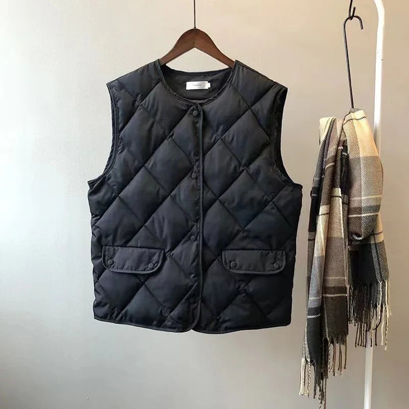 Black quilted sleeveless vest on wooden hanger next to beige and brown plaid scarf on white rack