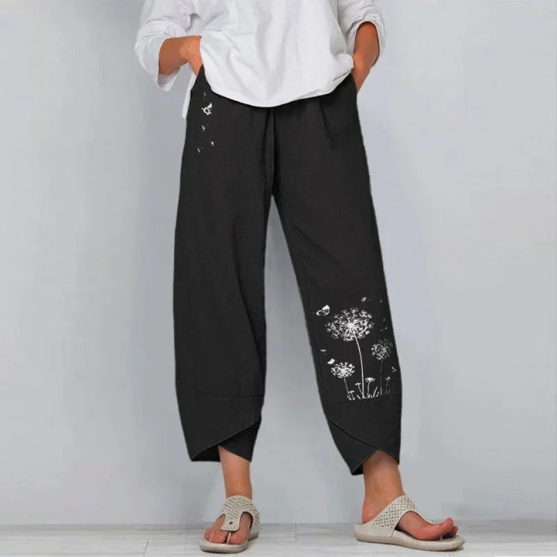 Person wearing black cropped pants with white dandelion and butterfly prints and a white top