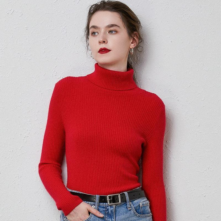 Woman wearing red ribbed turtleneck sweater and blue jeans with black belt against textured wall