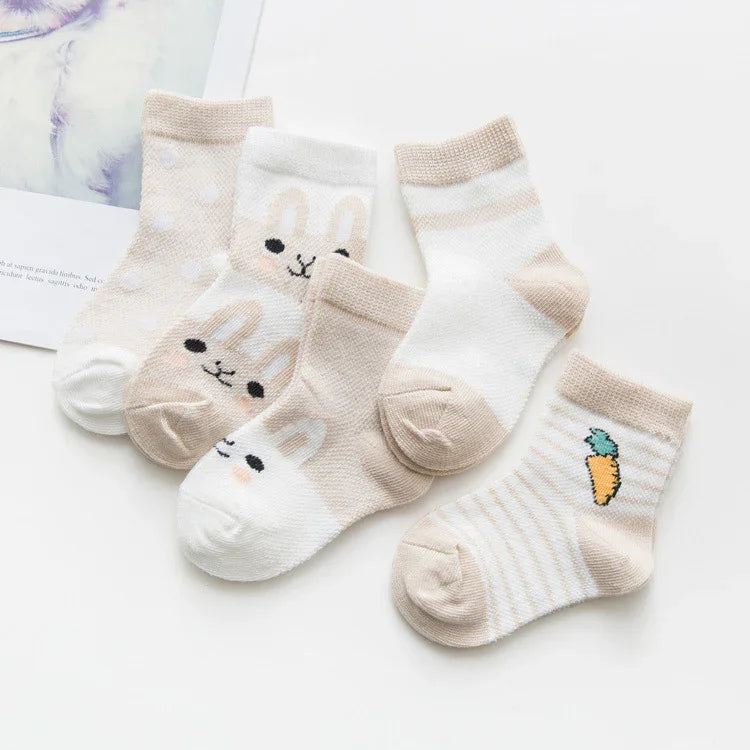 Five pairs of beige and white baby socks with bunny faces, polka dots, stripes, and carrot design