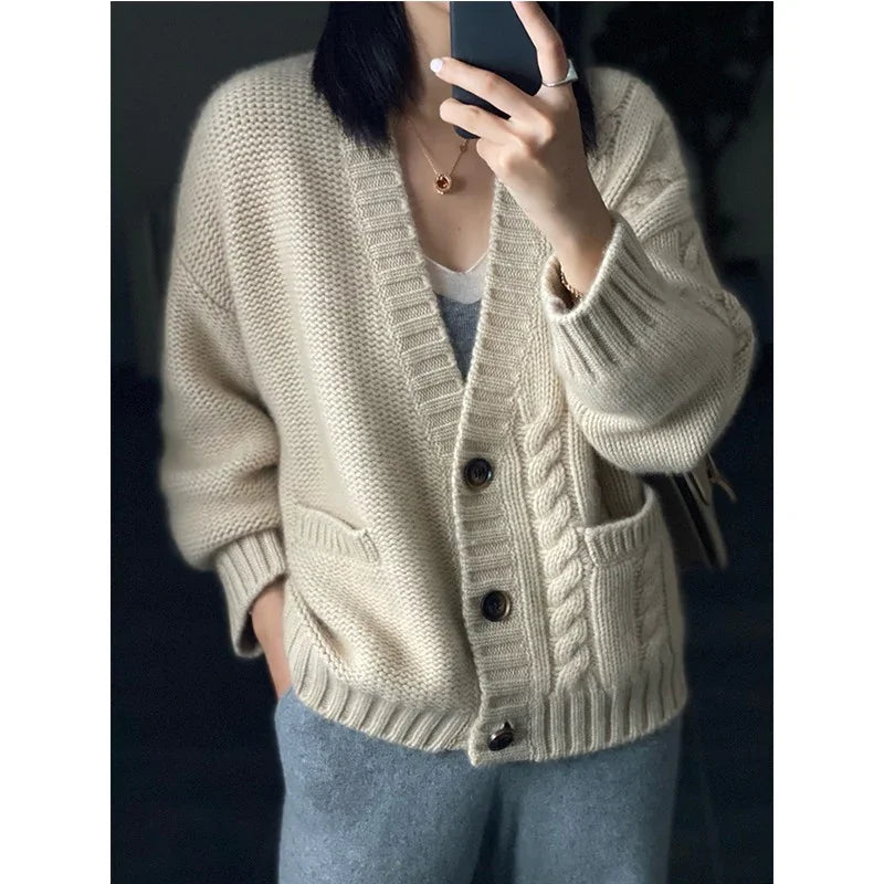 Person wearing cozy cream knit cardigan with cable pattern and pockets, paired with gray pants