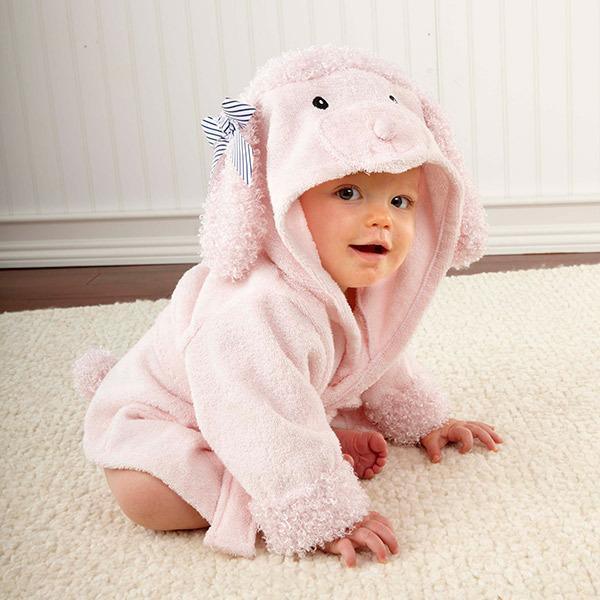 Baby wearing a soft pink lamb-themed hooded robe with a striped bow, crawling on white carpet