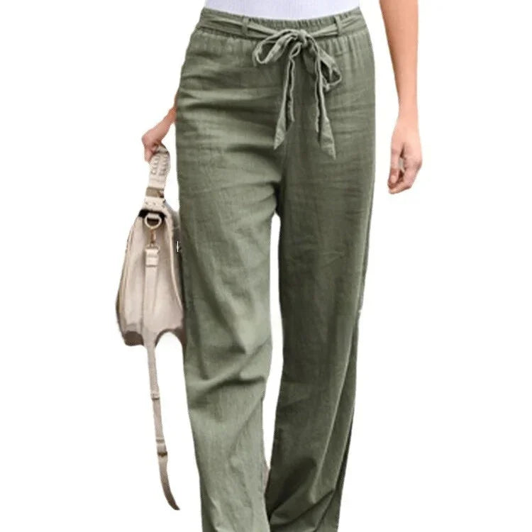 Woman wearing olive green drawstring linen pants holding beige handbag