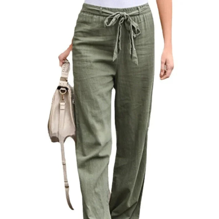 Woman wearing olive green drawstring linen pants holding beige handbag
