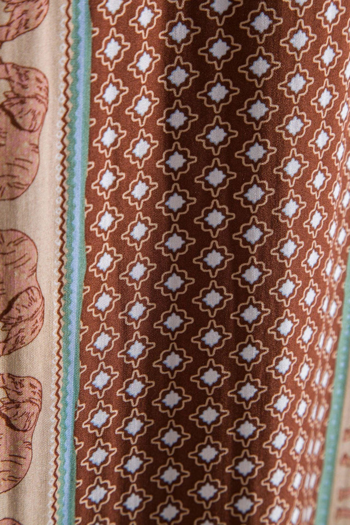 Close-up of fabric with brown geometric pattern and green bordered design on textured cloth