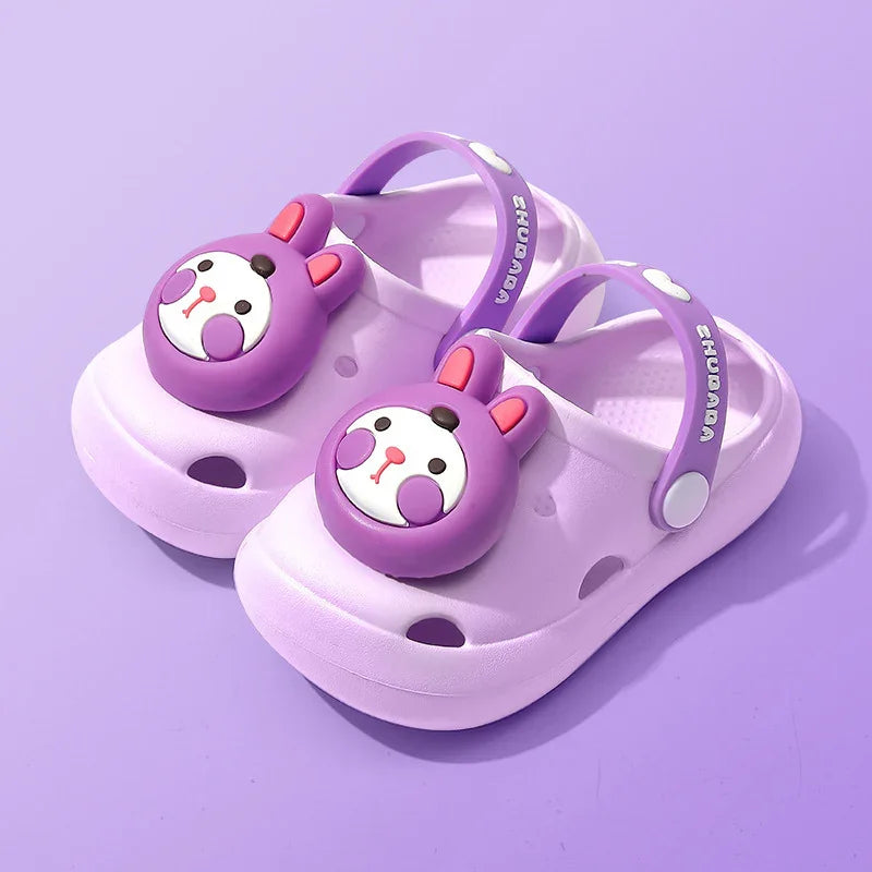 Children's purple clogs with bear face embellishments and adjustable back straps on purple background