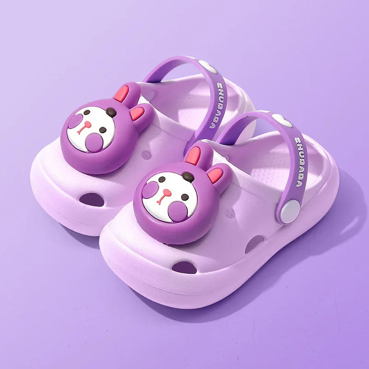 Children's purple clogs with bear face embellishments and adjustable back straps on purple background