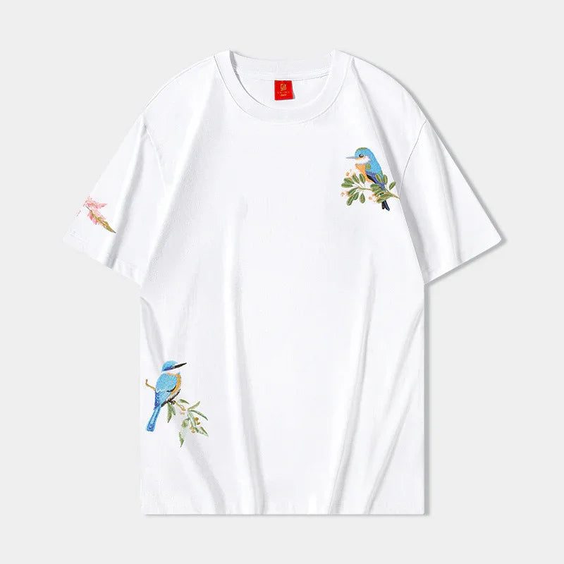 White t-shirt with blue bird embroidery on chest, sleeve, and lower side, nature-inspired design
