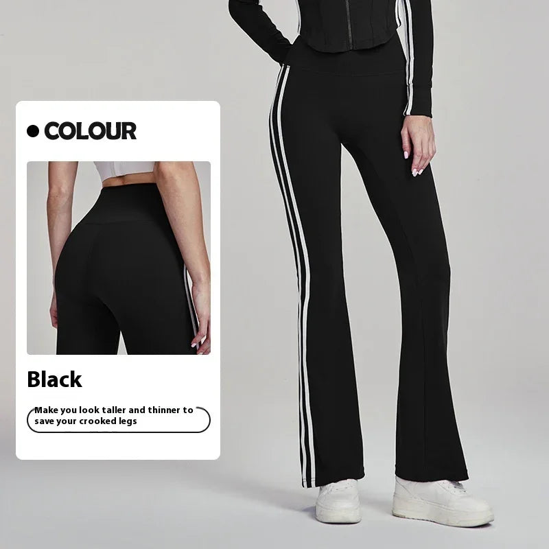 Black flared pants with white side stripes enhancing leg shape, styled with white sneakers and a black top.