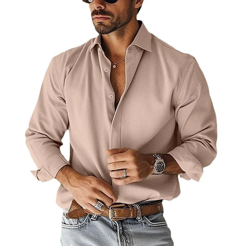 Man wearing beige button-up shirt, brown leather belt, light blue jeans, watch, rings, and sunglasses