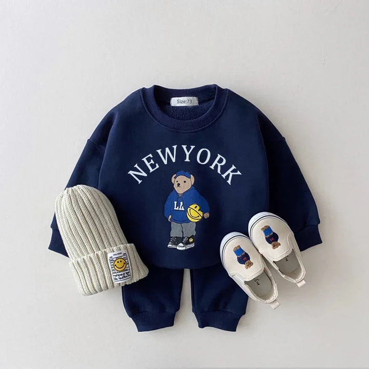 Navy blue toddler outfit with New York bear print, gray knit hat, and matching slip-on shoes