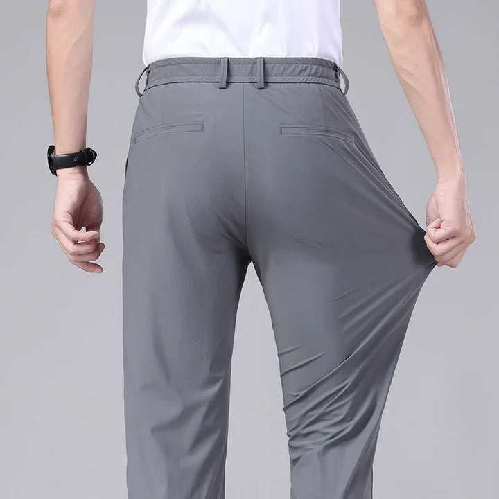 Rear view of person wearing stretchy gray trousers, demonstrating fabric elasticity by pulling pant leg