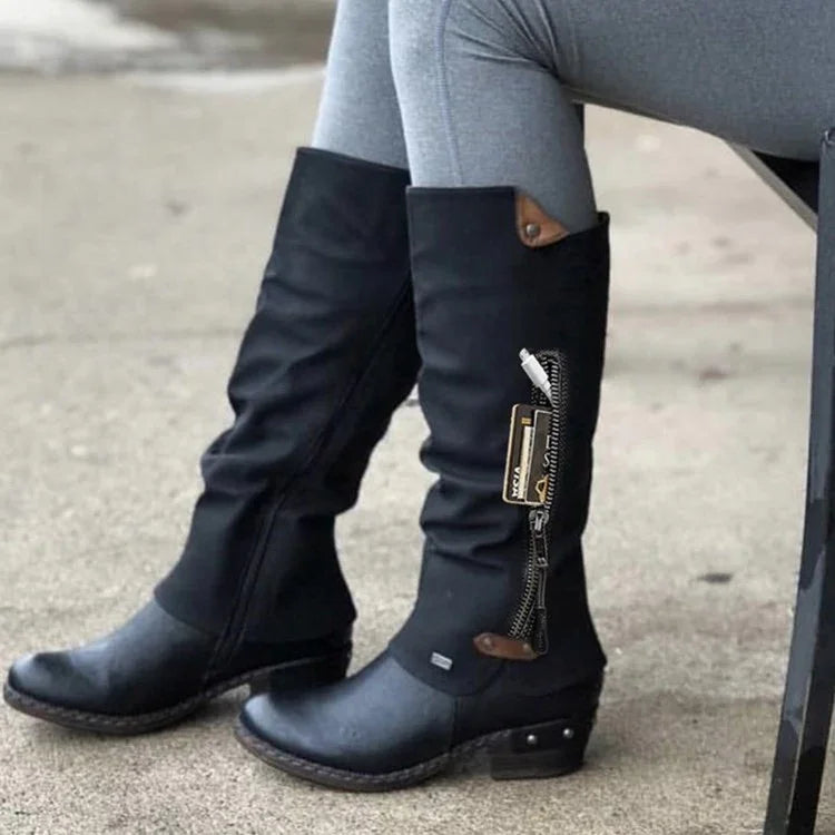 Black tall leather boots with side zipper detail worn with gray leggings outdoors