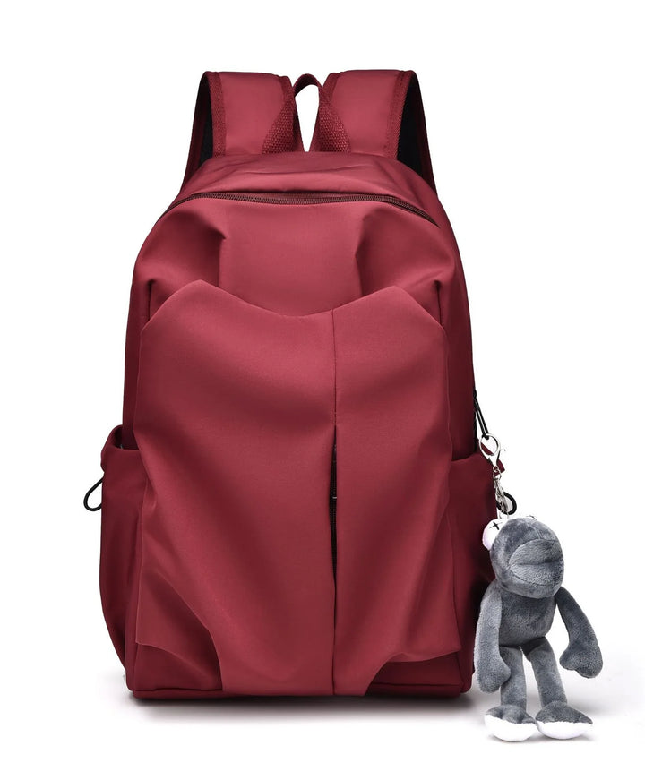 Red backpack with front pockets and attached gray plush keychain on white background
