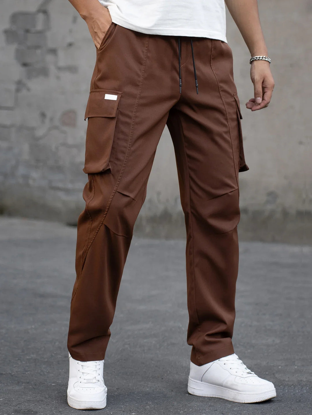 Man wearing brown cargo pants with side pockets and white sneakers on urban street