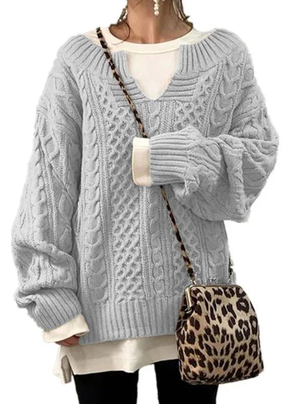 woman wearing light gray cable knit oversized sweater with white layered top and leopard print crossbody bag