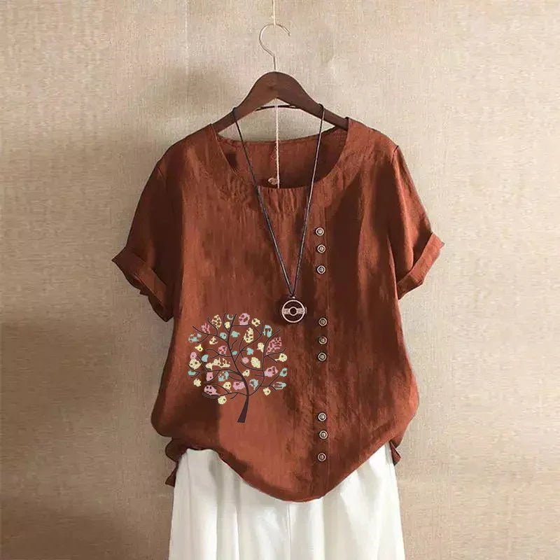 rust brown linen short-sleeve blouse with decorative tree print and buttons, paired with white pants