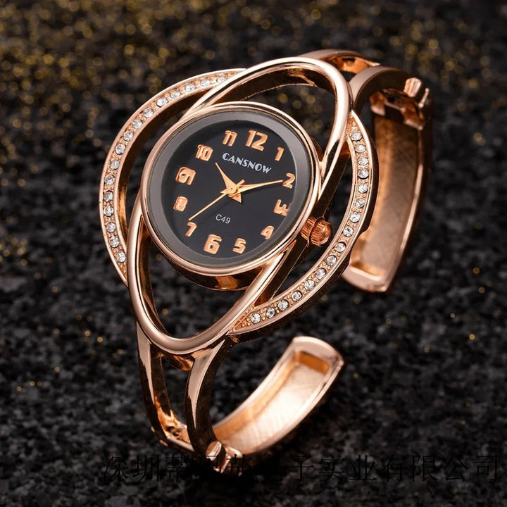 Rose gold women's bracelet watch with black dial, gold numerals, and crystal embellishments
