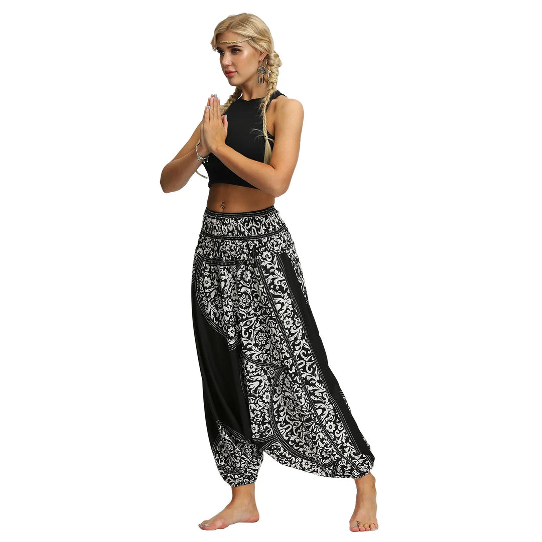 Woman in black crop top and black white patterned harem pants posing barefoot in yoga meditation stance