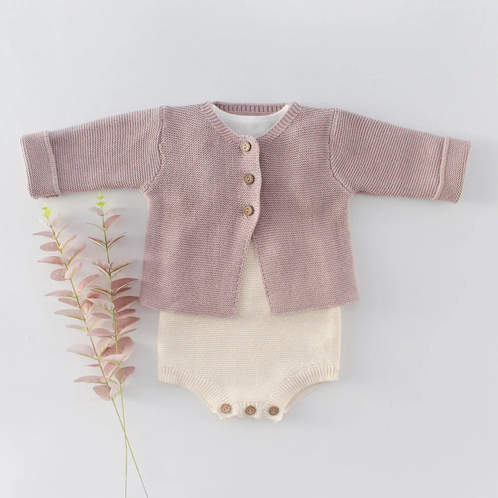 Baby knitted outfit with mauve cardigan and cream romper, wooden buttons, styled with pink foliage