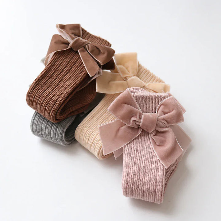 Set of cozy ribbed knit baby socks in brown, gray, beige, and pink with large velvet bows