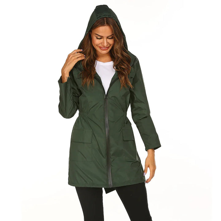 Woman wearing a dark green hooded zip-up raincoat with flap pockets, white shirt, black pants