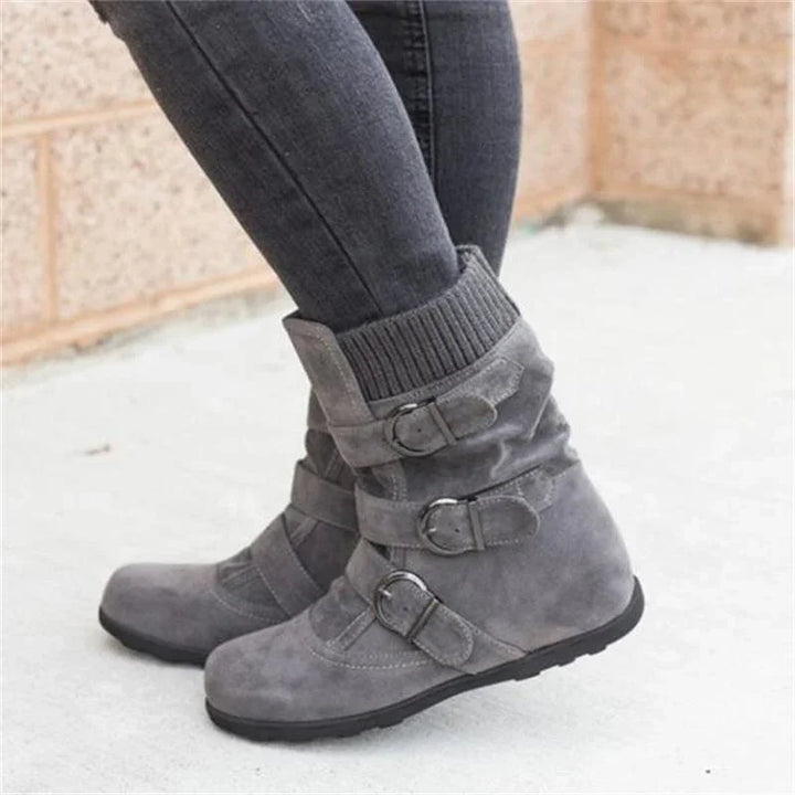 Grey suede ankle boots with triple buckle straps and ribbed knit cuffs worn with dark skinny jeans