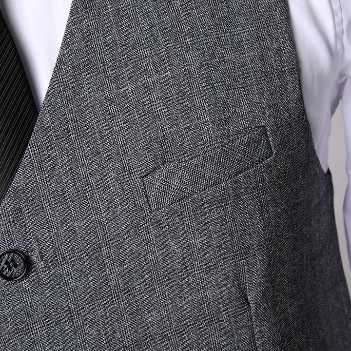 close-up of grey textured suit vest with a button over white shirt and black pinstripe tie
