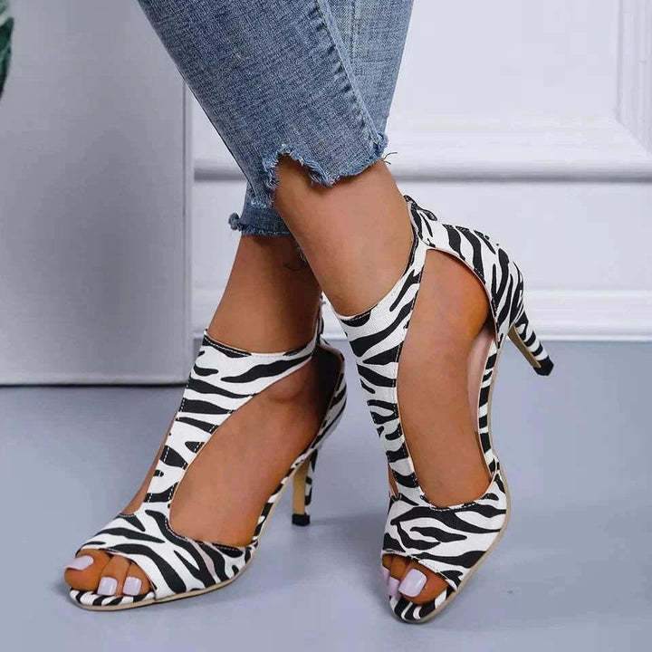 Woman wearing zebra print open-toe high heel shoes paired with cropped frayed hem jeans